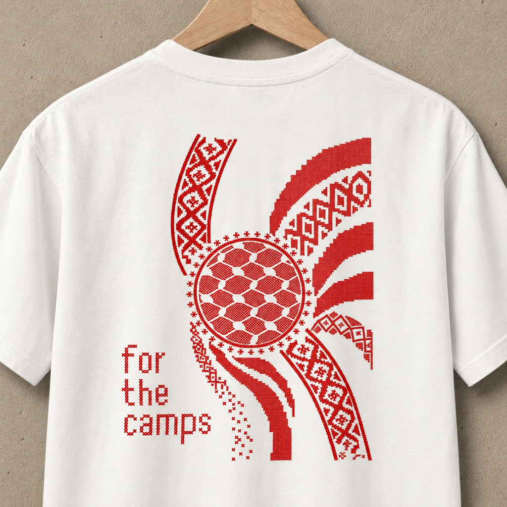 Close-up back view of Natural For the Camps Palestinian shirt on hanger with red tatreez and keffiyeh-inspired artwork.