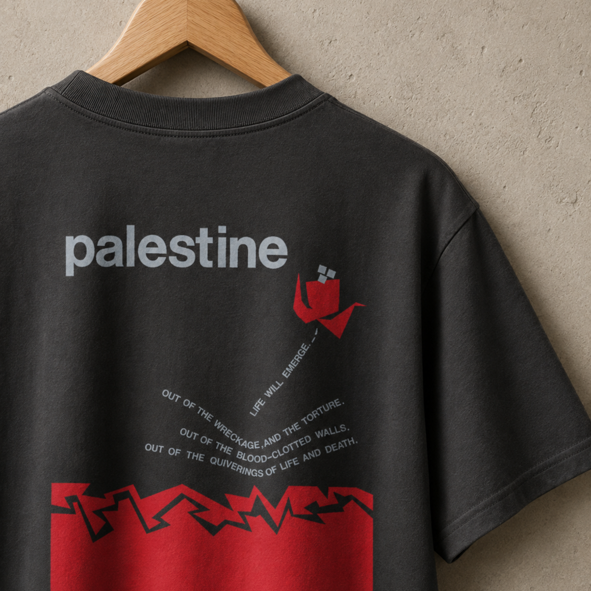 Back view of a faded black heavyweight T-shirt featuring the “Palestine — Life Will Emerge” graphic in gray and red.