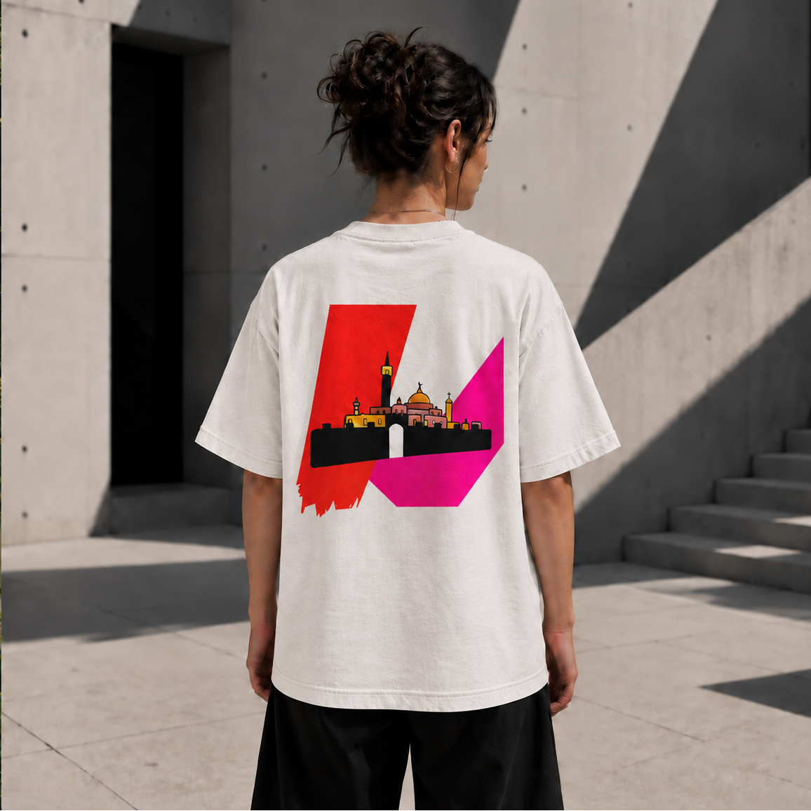 Back view of woman wearing a Faded Bone heavyweight Palestine Jerusalem T-shirt with archival artwork in a modern concrete architectural setting.