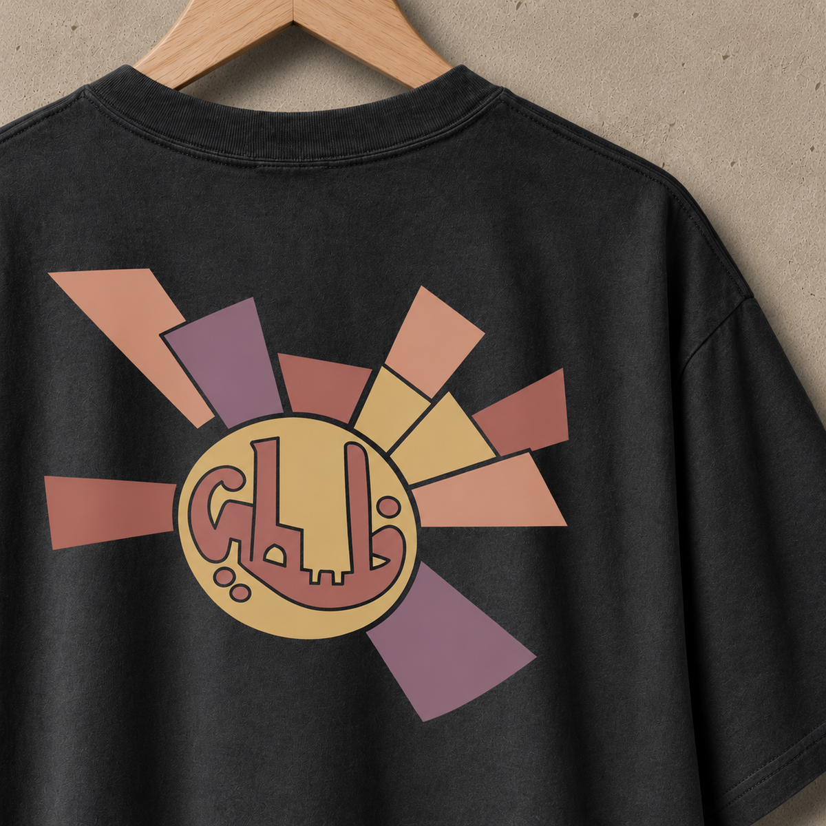 Close-up of Sun Emblem heavyweight faded black Palestinian T-shirt artwork with circular Arabic medallion and muted geometric sunburst.
