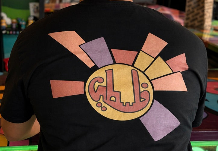Close-up back view of black lightweight Sun Medallion Palestinian T-shirt with colorful geometric medallion artwork.
